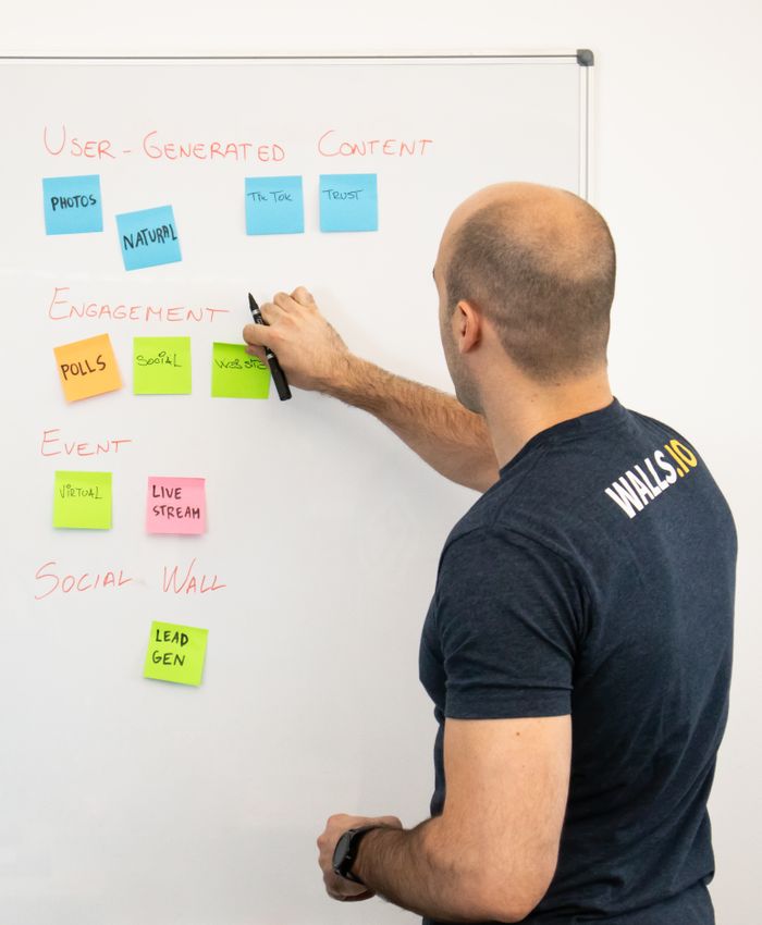 Man reviewing marketing content strategies with sticky notes on a whiteboard.